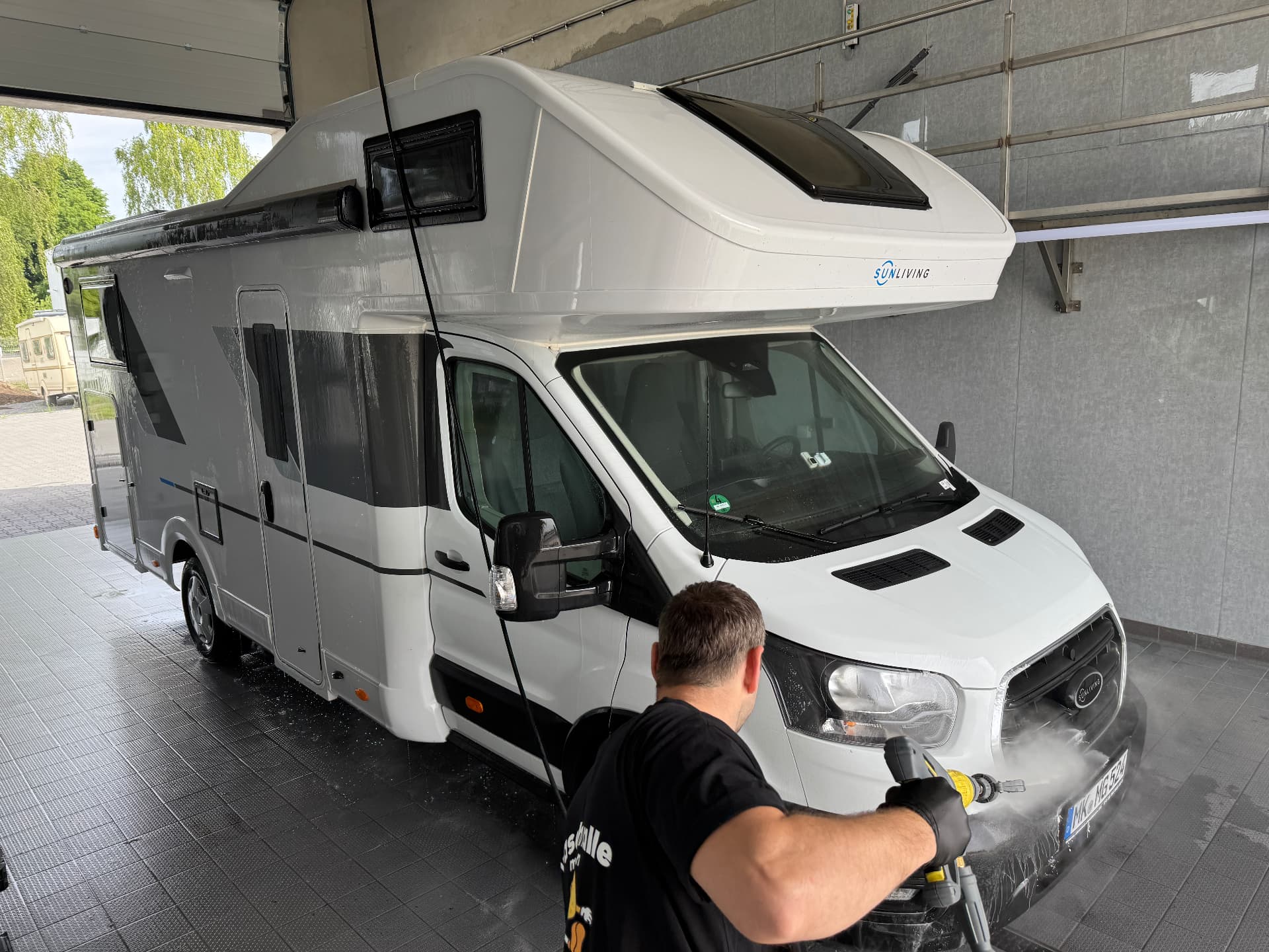 Frontwäsche eines Wohnmobils mit Hochdruckreiniger in der Waschhalle