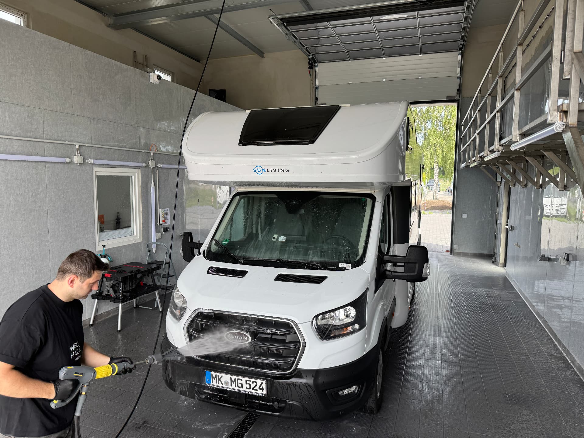 Mitglied des Waschhalle-Teams reinigt die Front eines Wohnmobils