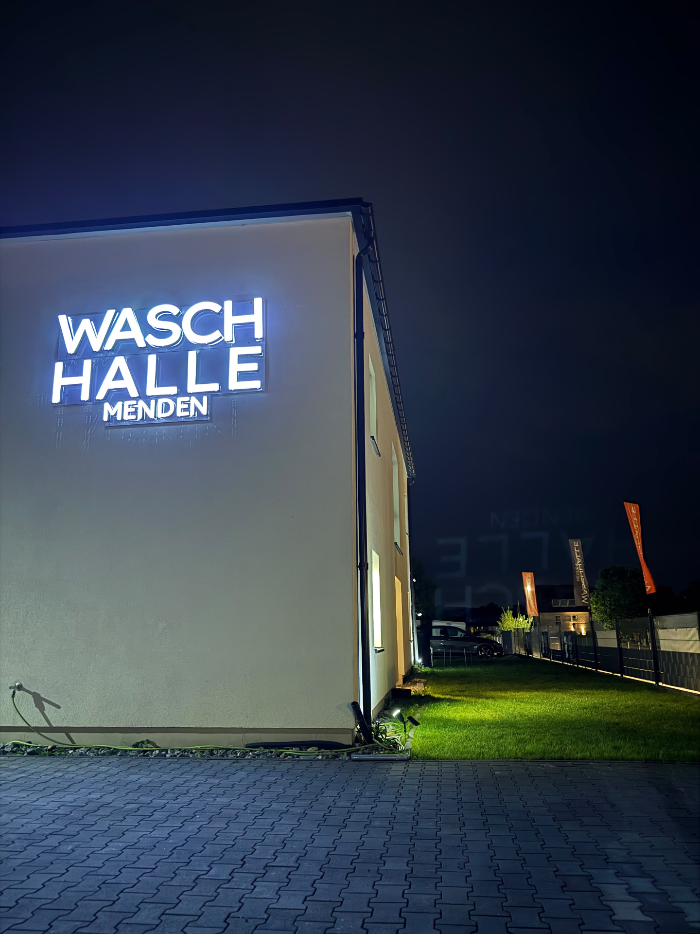 Außenansicht der Waschhalle Menden bei Nacht mit leuchtendem Schriftzug