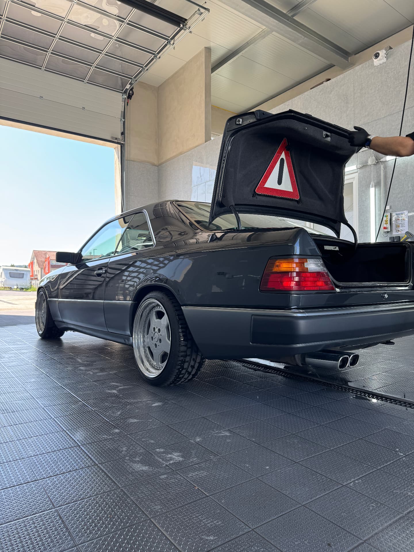 Coupé bei der Handpflege direkt am offenen Tor, mit geöffneter Heckklappe